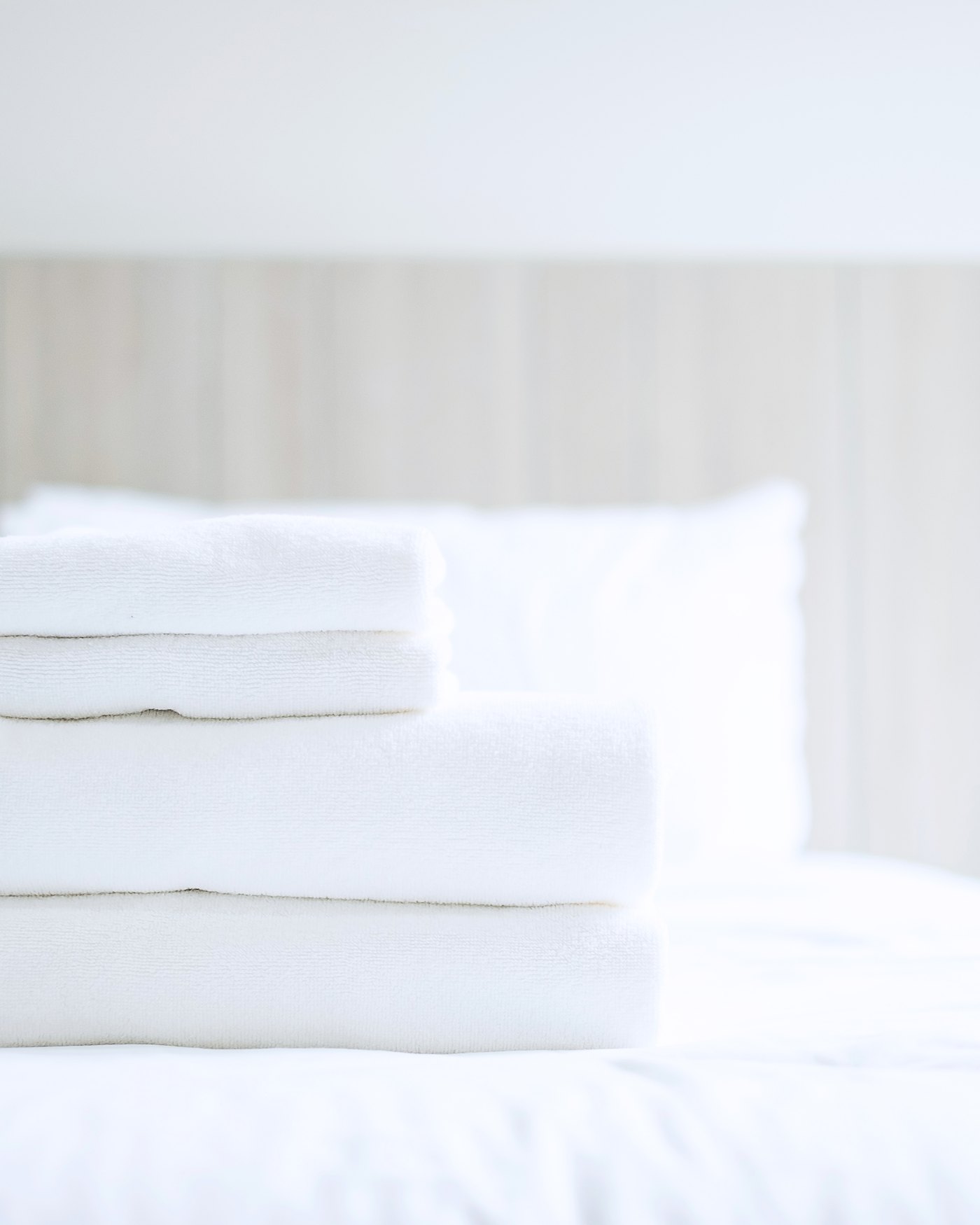 Folded towels and washcloth set out on a freshly made bed